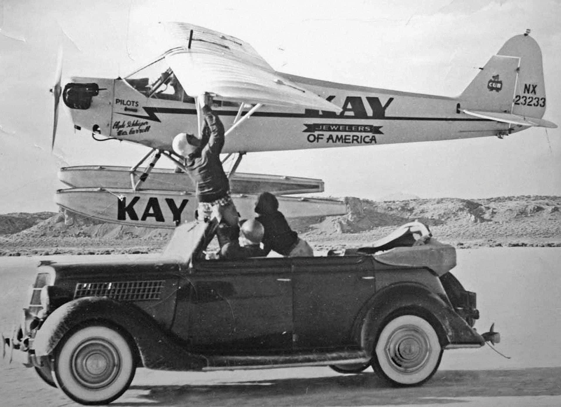 Wes Carroll and Clyde Schlieper were kept aloft thanks to canned fuel and other supplies passed up from a fast-moving 1935 Ford convertible. This picture also appears to demonstrate servicing the wingtip navigation light.
